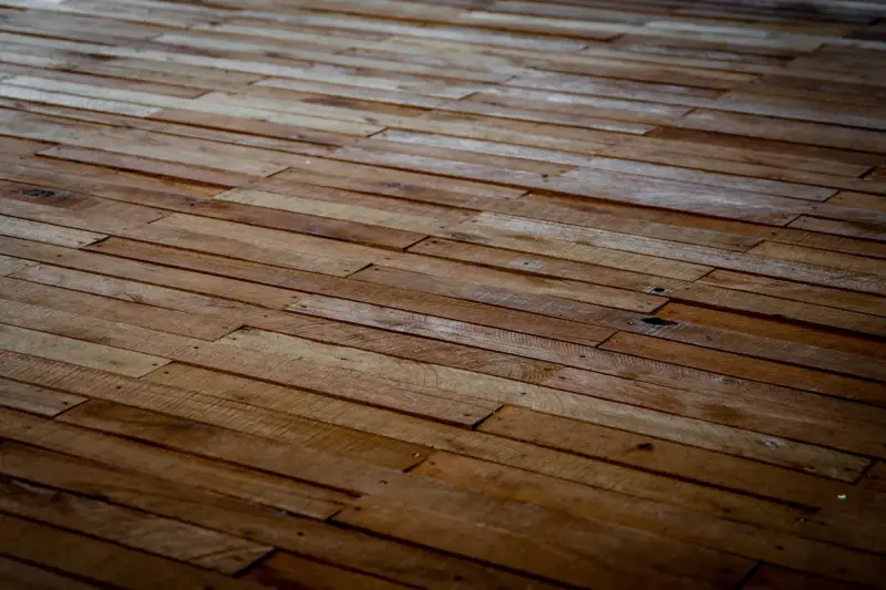 Wide view of a rustic wooden floor with long staggered planks in warm brown tones