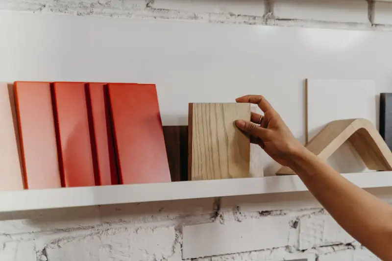 Hand picking a wood flooring sample from a shelf of tile and wood samples