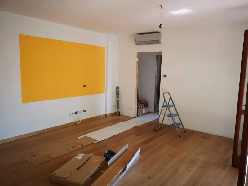 Apartment under renovation with new oak flooring, a step ladder and boxes of planks
