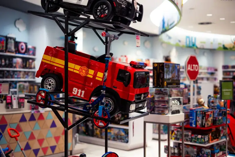 Toy store interior with a large red toy fire truck displayed above shelves of toys