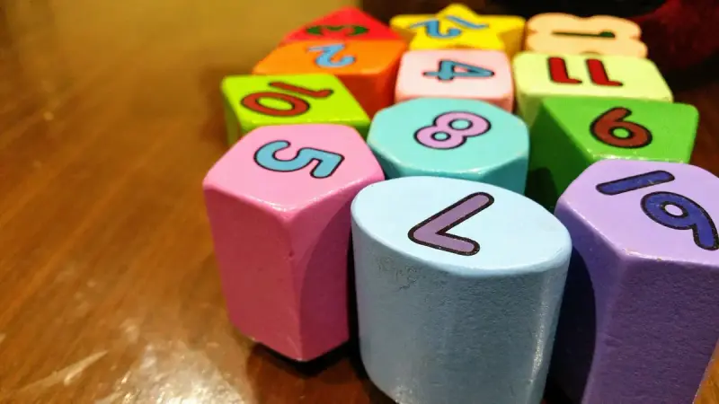 Pastel wooden shape blocks printed with large numbers on a wooden table