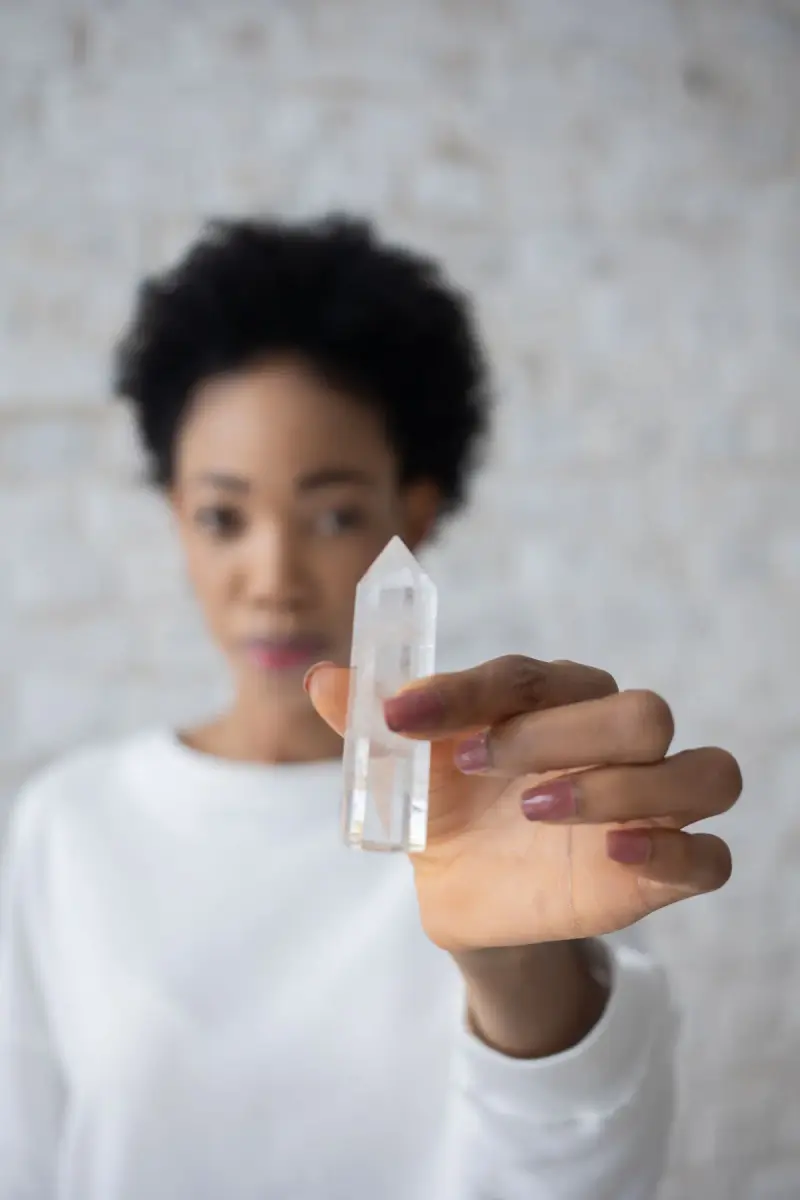 Woman holding a clear quartz crystal point toward the camera