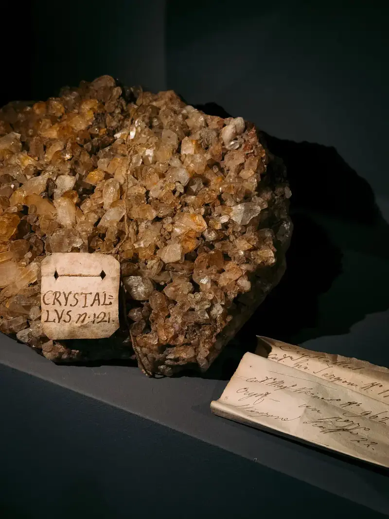 Quartz crystal mineral specimen in a museum case with old handwritten labels