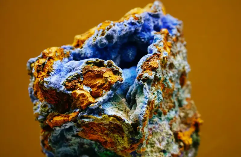 Blue azurite and orange limonite mineral specimen on an amber backdrop