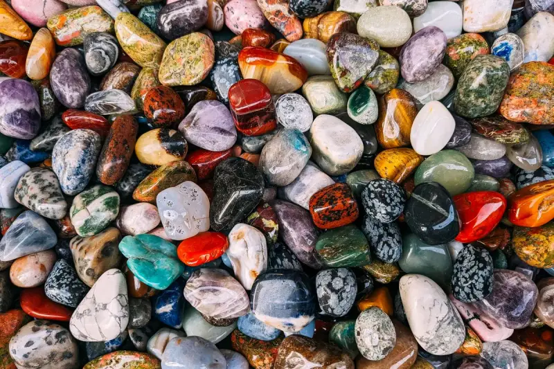 A dense layer of polished tumbled stones in red, blue, green, white and amber