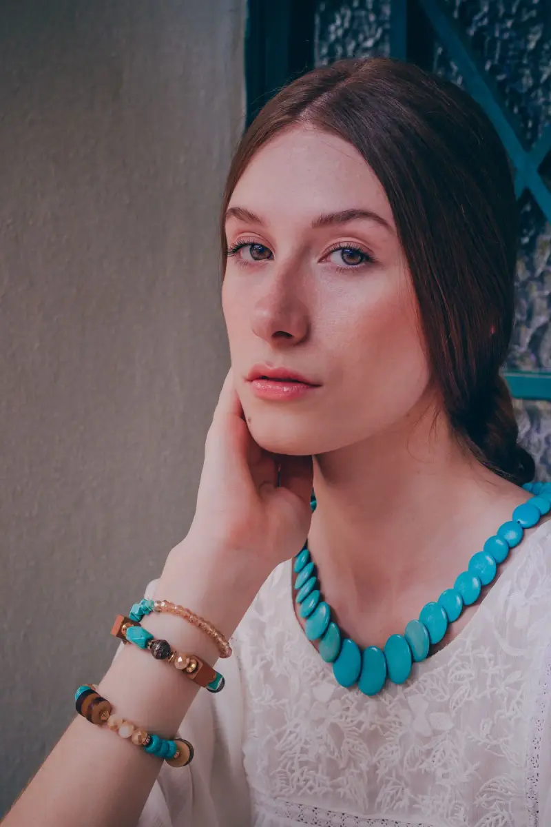 Woman in a white lace top wearing a turquoise slab necklace and beaded bracelets