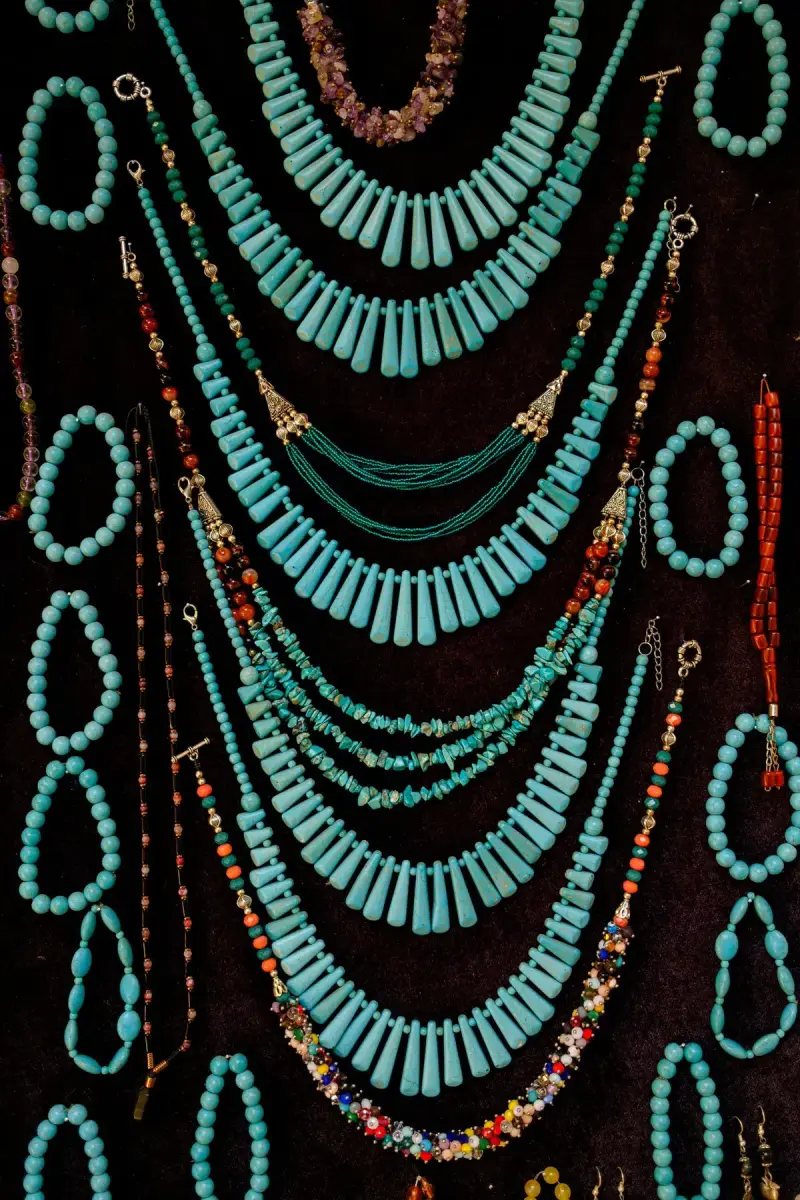 Rows of handmade turquoise bead necklaces hanging in a vendor display