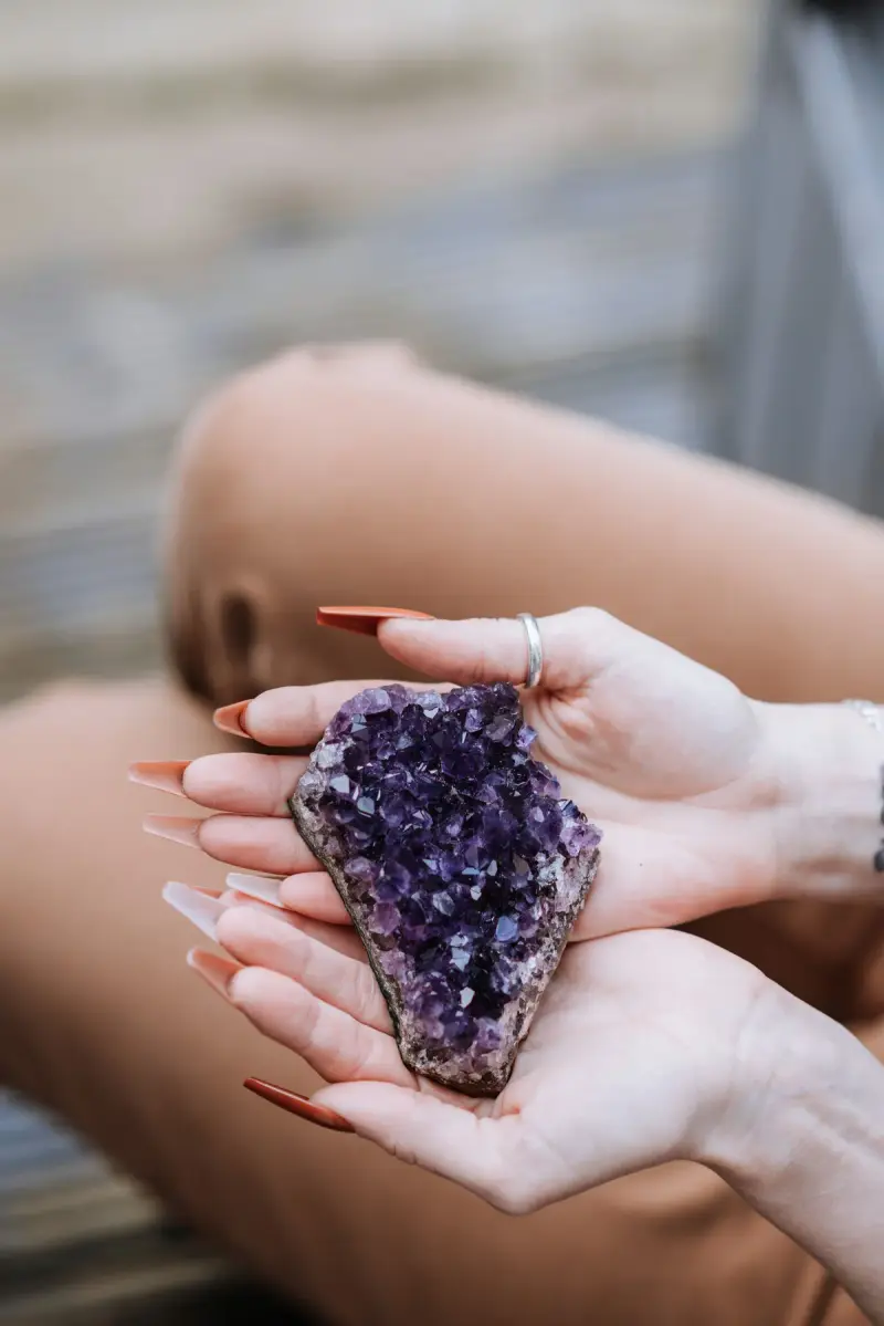 Woman holding a raw amethyst cluster in both hands