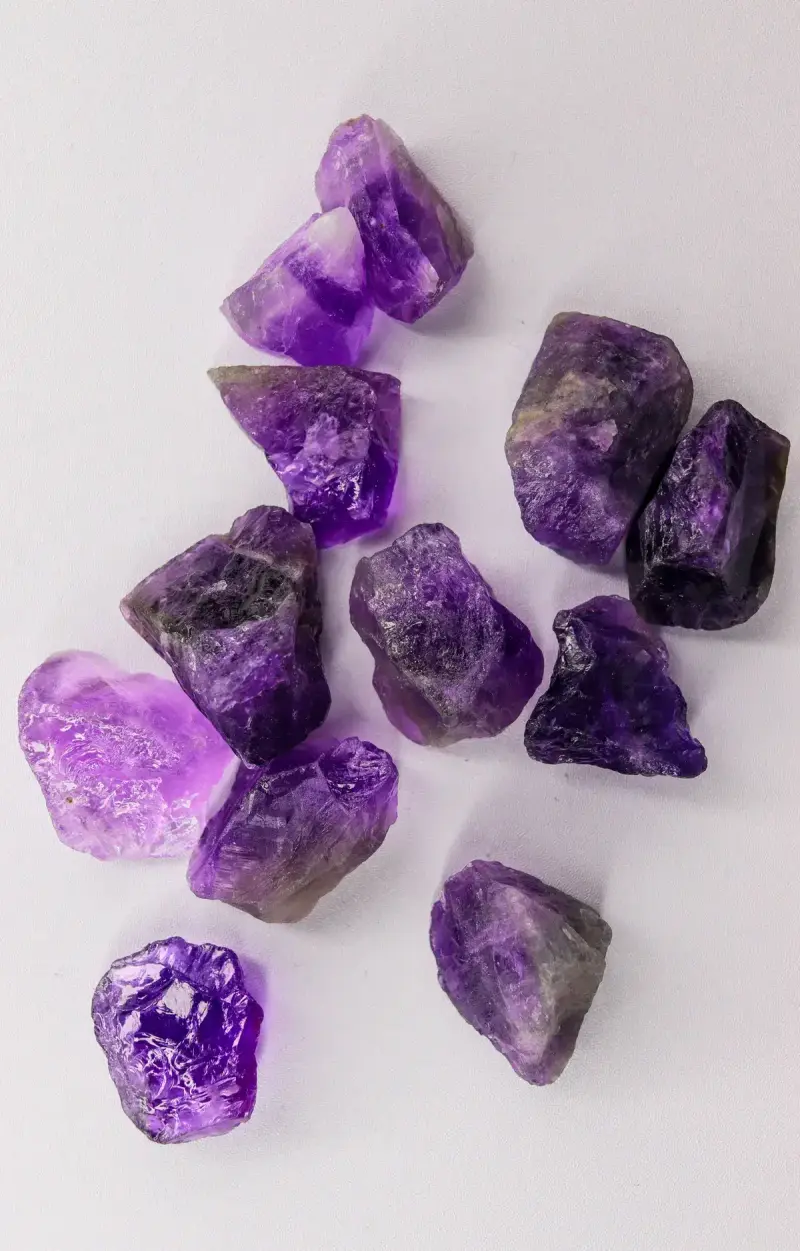 Raw purple amethyst crystal points scattered on a white surface