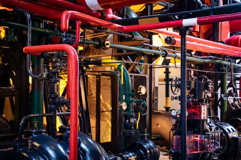 Red and green pipework, valves and pump housings crowding a historic pumping station
