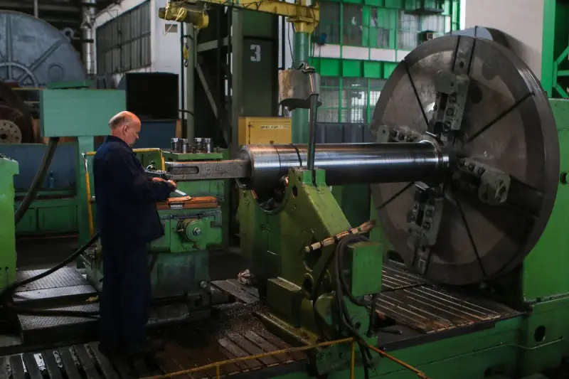 Worker inspecting a large machine on an industrial plant floor