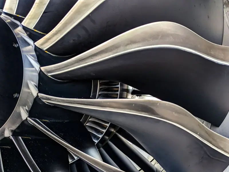 Close-up of curved fan blades inside a large turbine engine