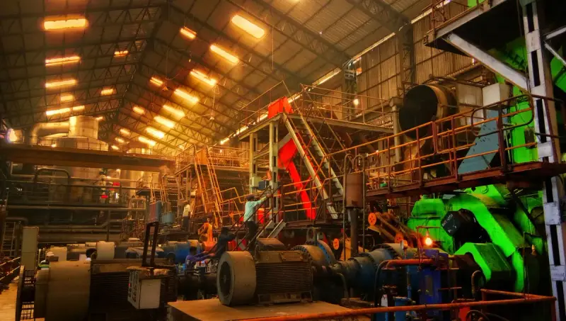 Plant interior with big motors, stairways and green machinery lit by rows of warm lights