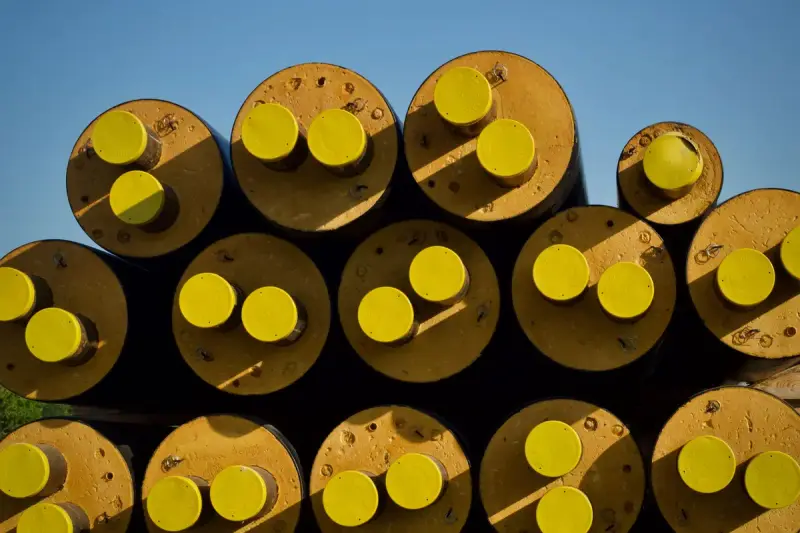 Insulated pipes stacked with bright yellow end caps against a blue sky