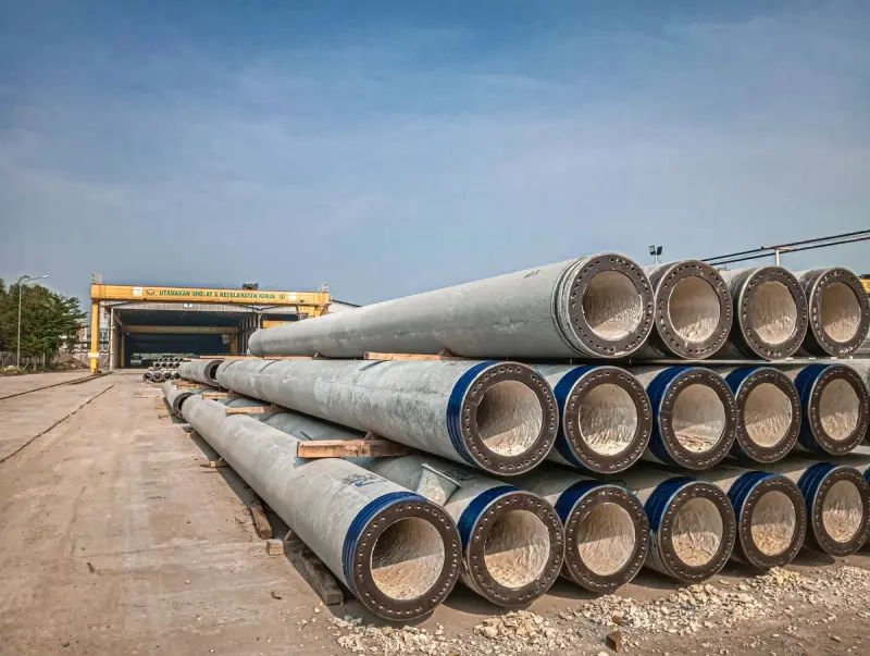 Stacks of concrete pipes with blue-banded ends stored in an outdoor yard
