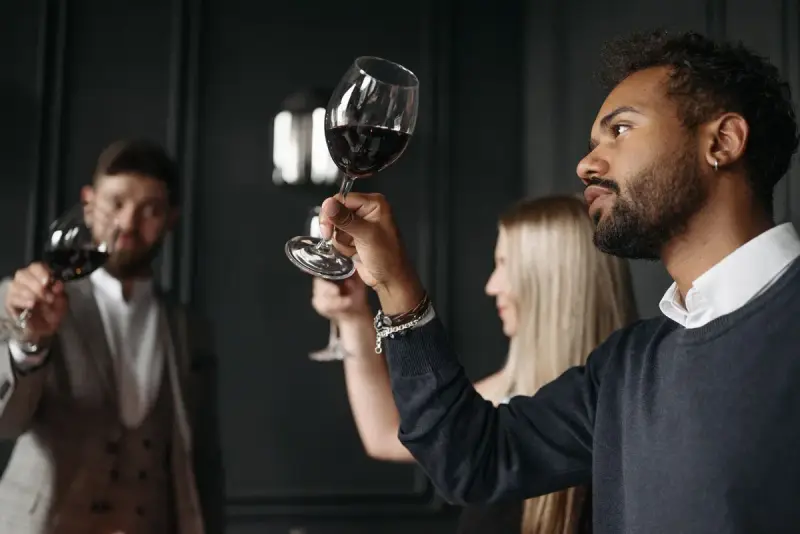 Guests at a wine tasting holding red wine up to the light to judge its color