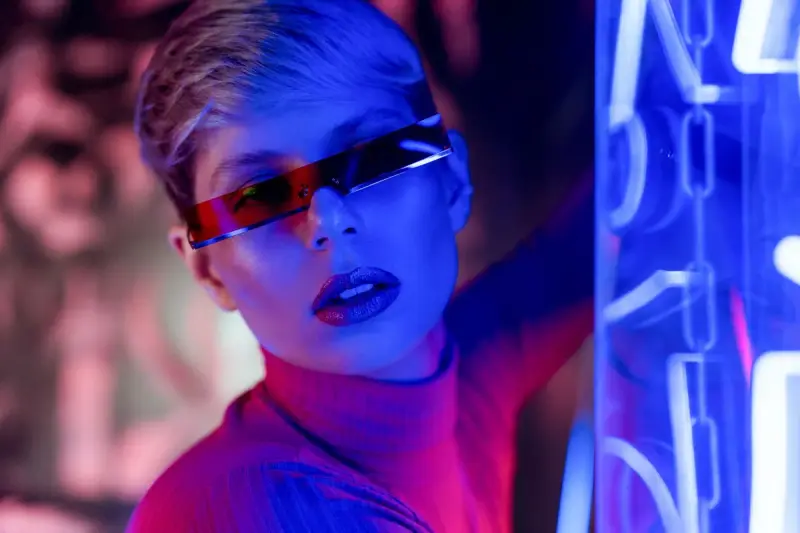 Woman in slim red visor sunglasses in blue and pink neon light