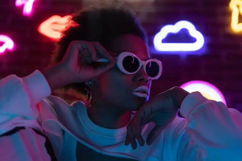 Woman in white oval sunglasses under neon lights
