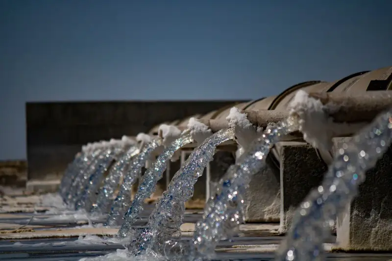 Clear water pouring from a row of outlet pipes into a basin