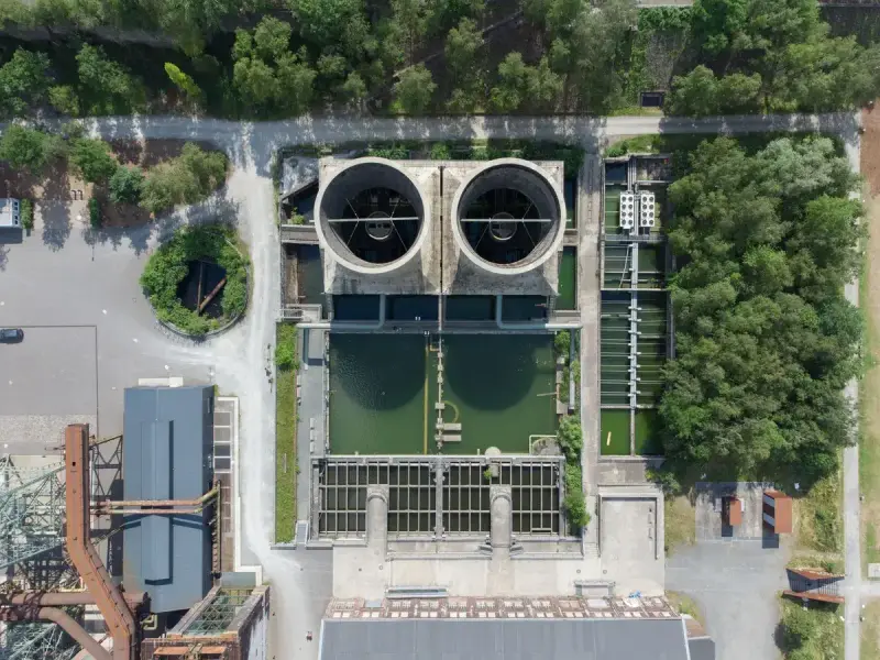 Overhead view of treatment basins and buildings at an industrial water facility in a green setting