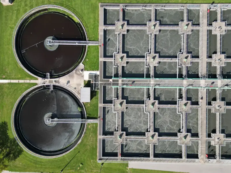 Two circular clarifiers beside a grid of filtration tanks at a wastewater plant