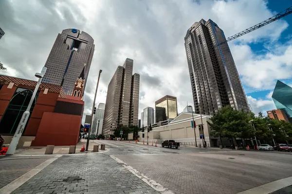 Downtown Dallas skyscrapers and a wide empty street under a cloudy sky