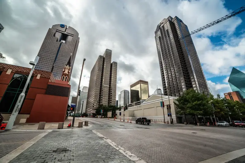Downtown Dallas skyscrapers and a wide empty street under a cloudy sky