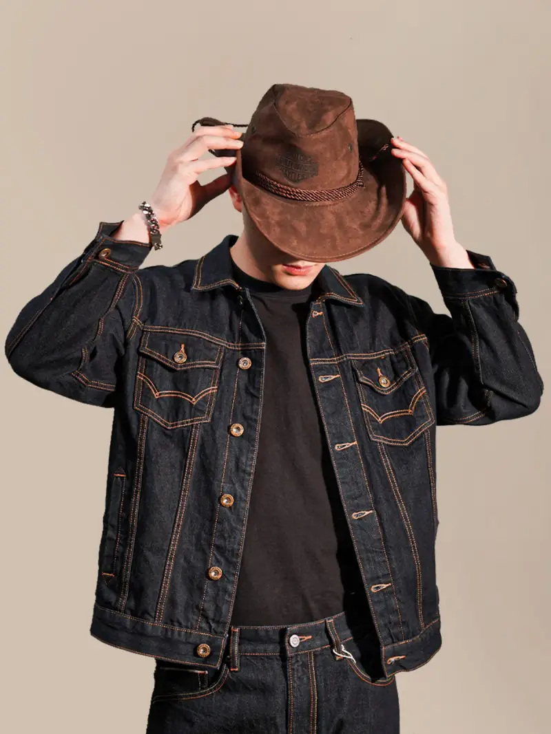 Man shaping the brim of a brown suede cowboy hat in a dark denim jacket