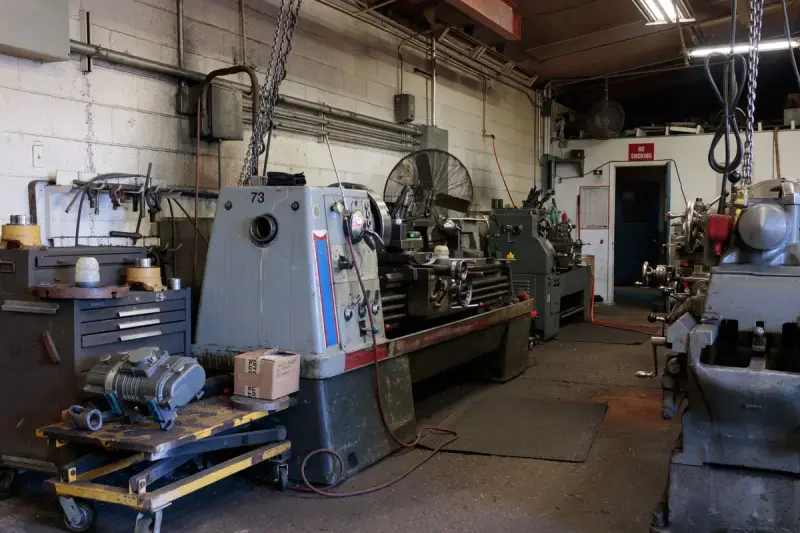 Machine shop floor with a large engine lathe, workbenches and more lathes along the walls