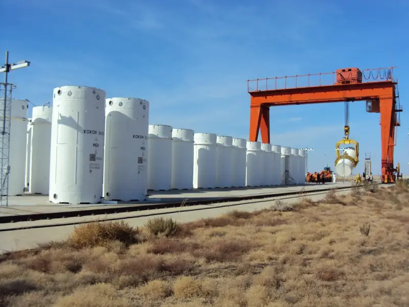 Rows of large concrete dry casks holding spent nuclear fuel on an outdoor storage pad