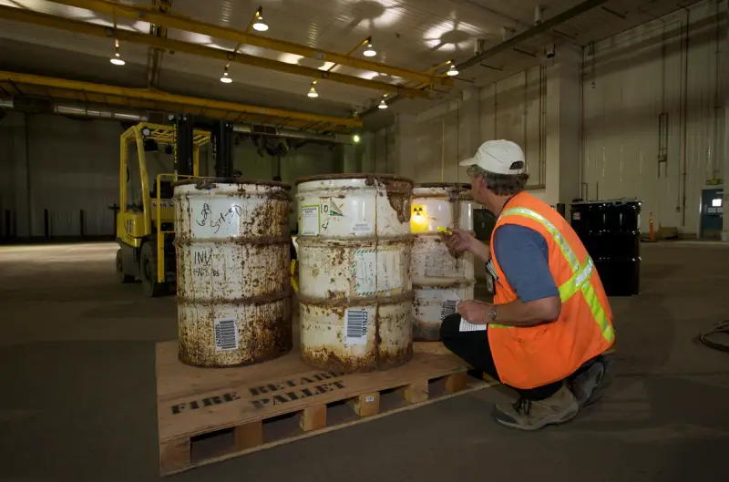Technician inspecting a waste drum at a mixed waste treatment facility