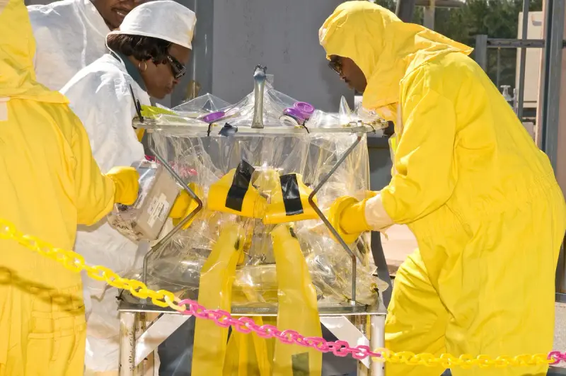 Workers using a glove box to handle samples for a radioactive waste tank