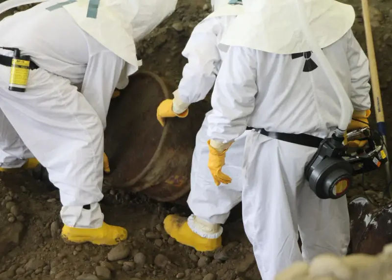 Excavator and crew recovering a waste container from an underground storage trench