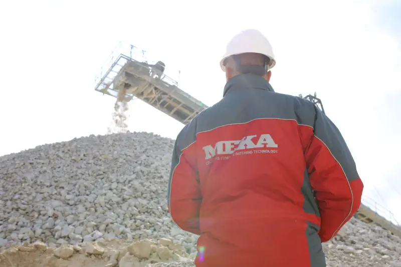 Worker at a gravel quarry watching a conveyor carry crushed stone