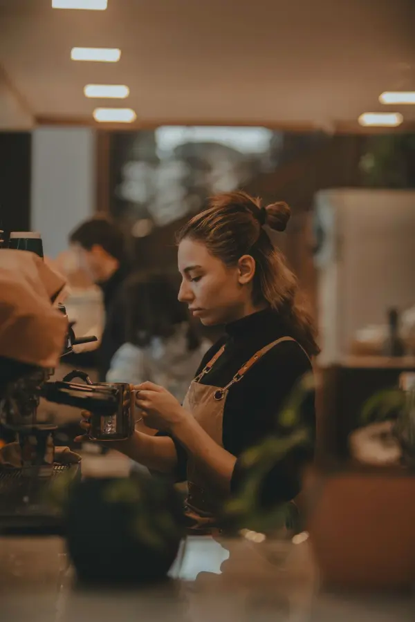 Woman preparing coffee behind a café counter