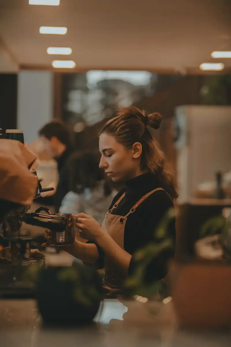 Woman preparing coffee behind a café counter