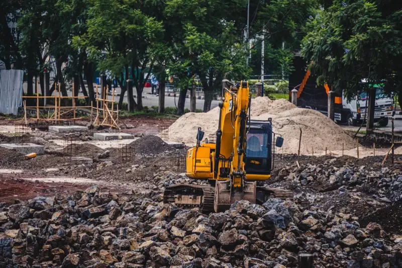 Yellow excavator working at an urban construction site among rocks