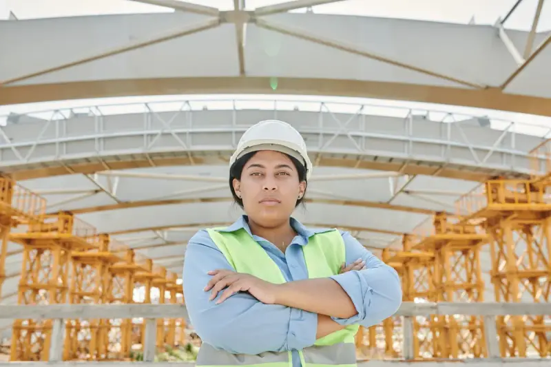 Female engineer in hard hat and vest at a site with steel structure behind