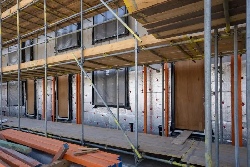 Residential building under construction with scaffolding, window openings and insulation boards