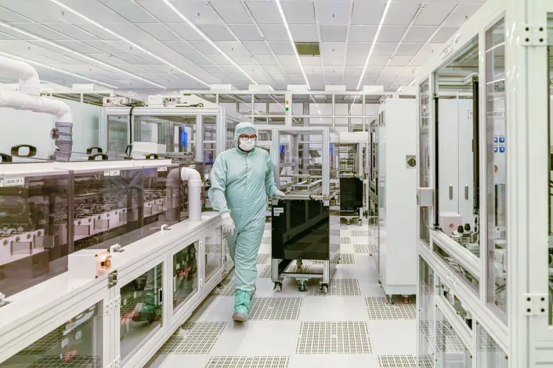 Technician in a cleanroom suit walking through a high-tech cleanroom