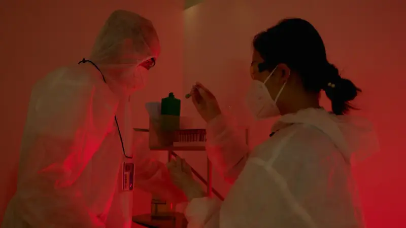 Two researchers in protective suits working side by side in a laboratory