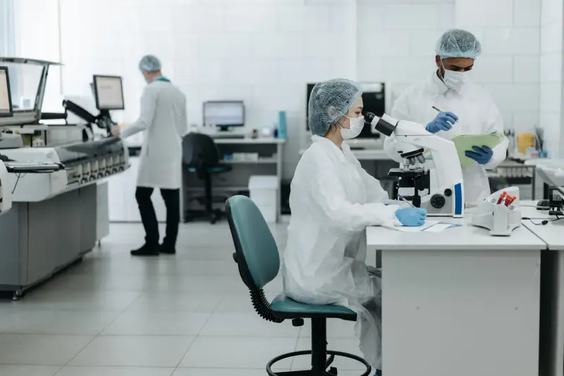 Researchers in protective gear examining samples at a laboratory bench
