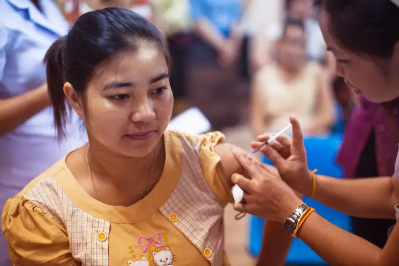 Health worker giving a young woman a vaccination in her upper arm