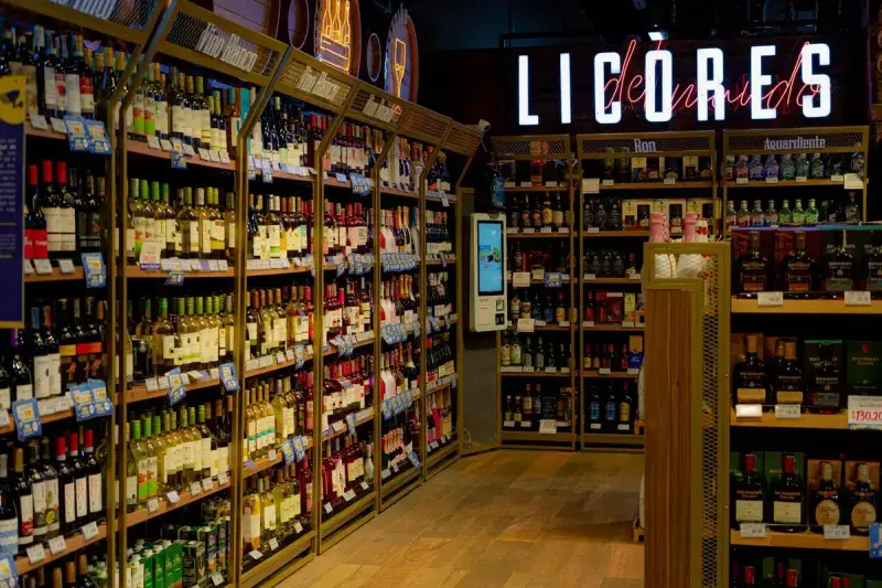 Retail liquor aisle with lit shelves of wine and spirits bottles grouped by category