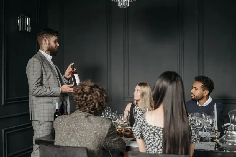 Sommelier presenting a bottle of wine to women and men seated at a tasting table