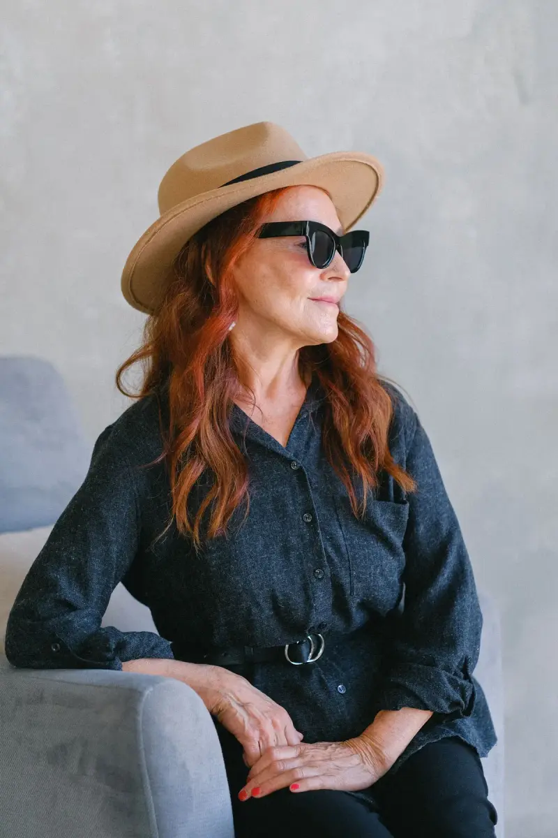 Red-haired woman in a camel fedora, sunglasses and belted denim shirt dress