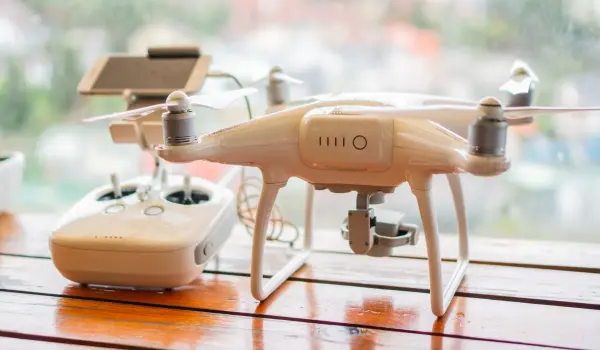 White quadcopter and its controller displayed on a table