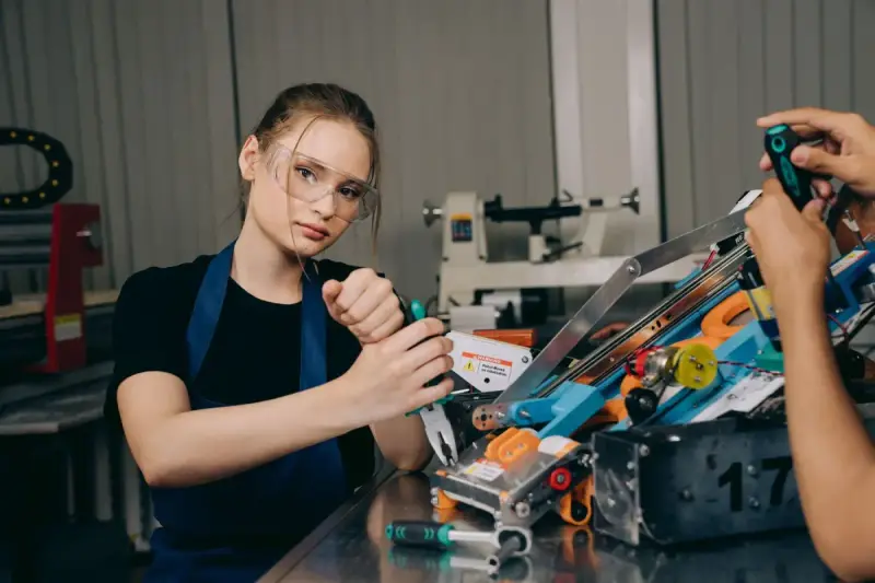 Woman wearing protective glasses working with mechanical components in a workshop