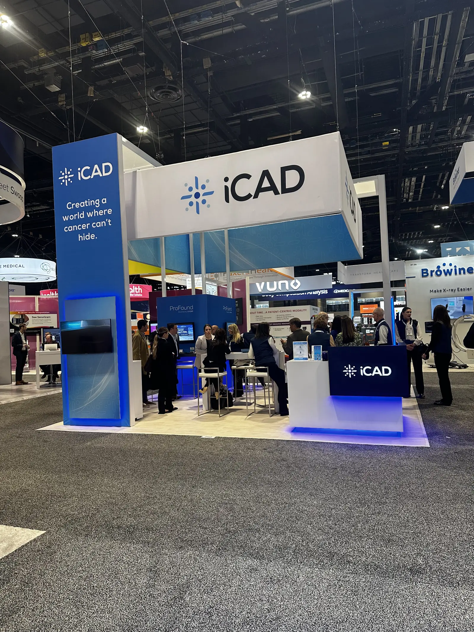 iCAD booth by Purple Exhibits: blue and white iCAD island booth with a tall branded tower, overhead header sign