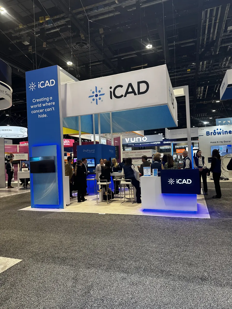 iCAD booth by Purple Exhibits: blue and white iCAD island booth with a tall branded tower, overhead header sign